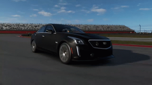 A Black Cadillac Is Driving Down A Track GIF