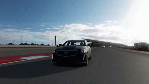 A Black Cadillac Is Driving Down A Track GIF