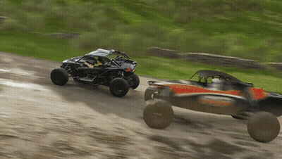 A Black Can-Am Buggy Is Driving Down A Dirt Road GIF