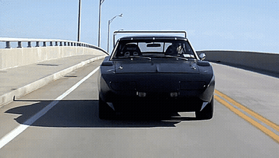 A Black Car Is Driving Down A Highway With A Yellow Line In The Middle GIF