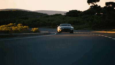 A Black Car Is Driving Down A Road With Trees In The Background GIF