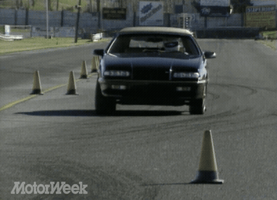 A Black Car Is Driving On A Road With A Motorweek Logo In The Corner GIF