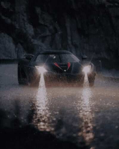 A Black Car Is Driving Through A Puddle Of Water GIF