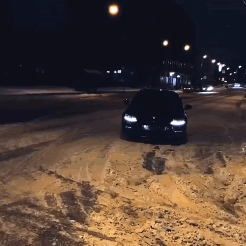 A Black Car Is Driving Through The Snow At Night GIF