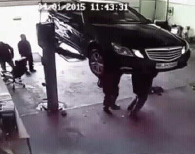A Black Car Is On A Lift In A Garage With A Time Stamp Of 11:45:31 GIF