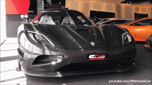 A Black Car Is Parked In Front Of A Building That Says ' Alan Glass ' On It GIF