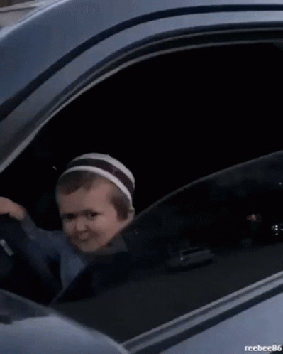 A Black Car Is Parked In Front Of A Building With A Reflection Of A Building In The Window . GIF