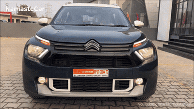 A Black Car Is Parked In Front Of A Building With The Words Namaste Car On The Bottom Left GIF
