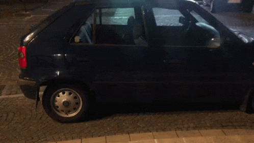 A Black Car Is Parked On A Cobblestone Sidewalk And Has A License Plate That Says ' Nc ' On It GIF