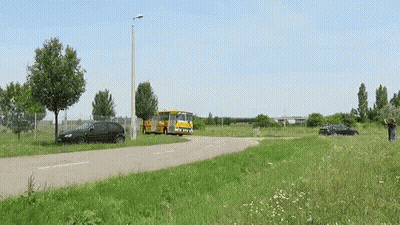 A Black Car Is Parked On The Side Of The Road Next To A Bus GIF