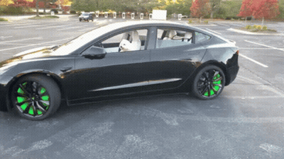 A Black Car With Green Wheels Is Parked In A Lot GIF