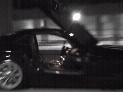 A Black Car With Its Doors Open Is Parked In A Parking Lot At Night . GIF