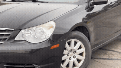 A Black Car With Silver Rims And A Black Hood Is Parked On The Side Of The Road GIF