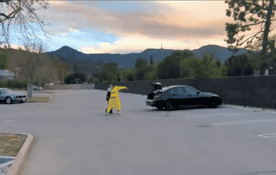 A Black Car With The Trunk Open Is Parked In A Parking Lot With Mountains In The Background GIF