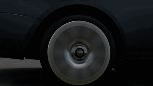 A Black Car With White Wheels Is Parked On A Street GIF