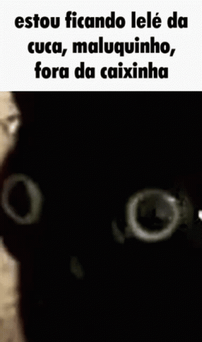 A Black Cat Is Looking At The Camera With A White Hand Behind It . GIF