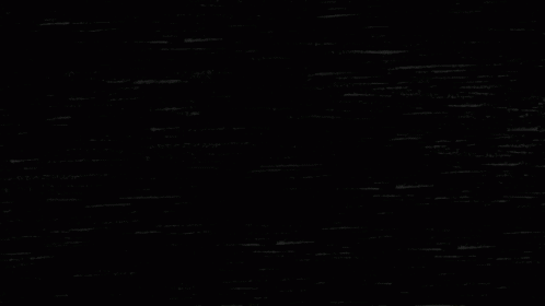 A Black Cat Is Looking Out Of A Hole With A Light Bulb Hanging From It . GIF