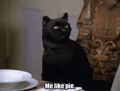 A Black Cat Sitting At A Table With The Words Me Like Pie Below It GIF