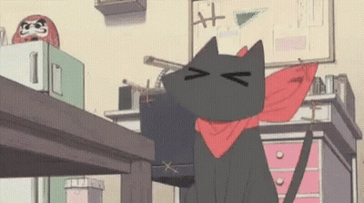 A Black Cat Wearing A Red Scarf Around Its Neck Is Sitting On A Desk . GIF
