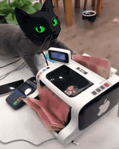 A Black Cat With Green Eyes Sits Next To A Machine That Has An Apple Logo GIF
