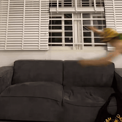A Black Couch In Front Of A Window With Blinds On It GIF
