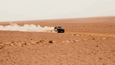 A Black Dacia Car Is Driving Through The Desert GIF