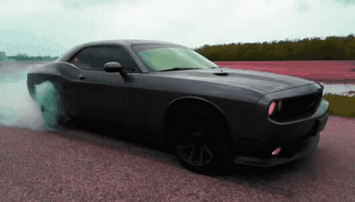 A Black Dodge Challenger Is Doing A Burnout On The Road GIF