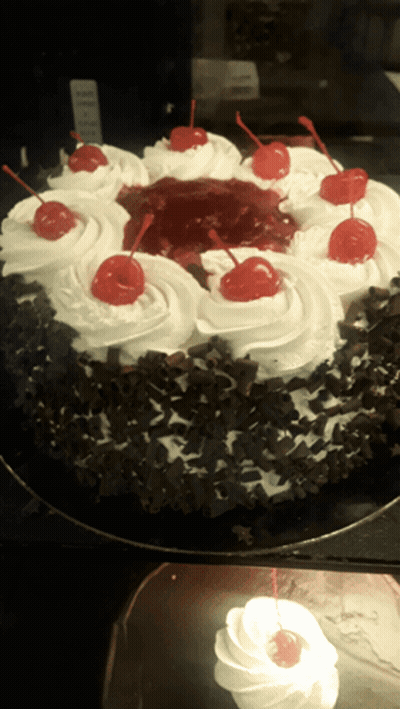 A Black Forest Cake With Whipped Cream And Cherries GIF