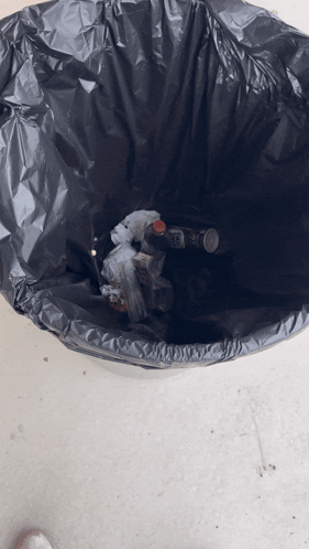 A Black Garbage Bag Filled With Bottles And Trash GIF