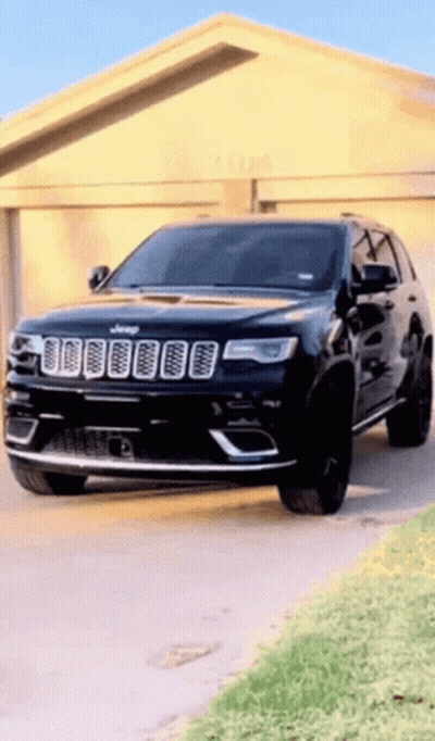 A Black Jeep Is Parked In Front Of A Garage Door GIF