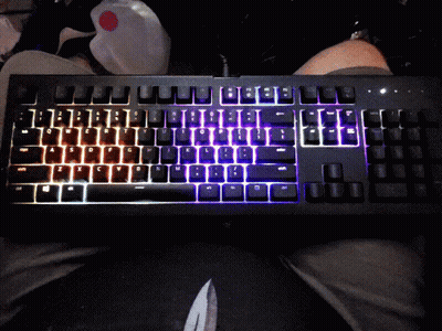 A Black Keyboard With Rainbow Colored Keys Is Sitting On A Persons Lap GIF