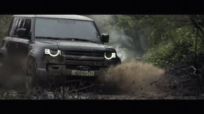 A Black Land Rover Defender Is Driving Through A Muddy Area GIF