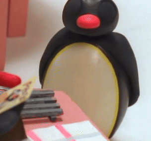 A Black Penguin With A Red Beak Is Sitting On A Table GIF