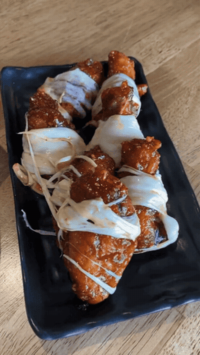 A Black Plate Topped With Fried Chicken Covered In Sauce And Cheese GIF