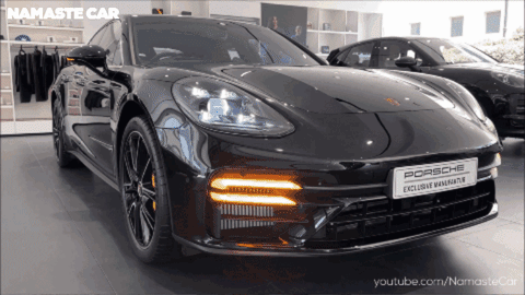 A Black Porsche Is Displayed In A Namaste Car Showroom GIF