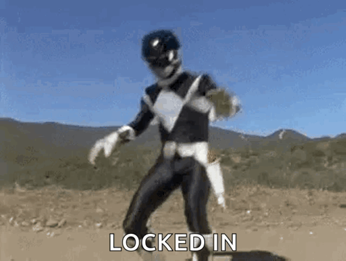 A Black Ranger From Power Rangers Is Dancing In The Dirt In Front Of Mountains . GIF
