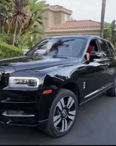 A Black Rolls Royce Car Is Parked In Front Of A House GIF