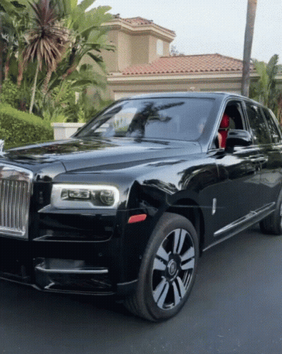 A Black Rolls Royce Is Parked In Front Of A House With Palm Trees GIF