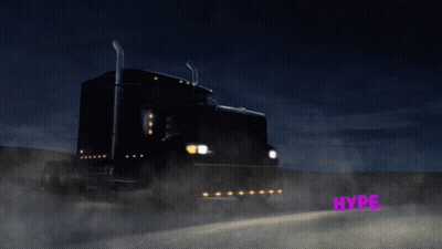 A Black Semi Truck Is Driving Down A Highway At Night GIF