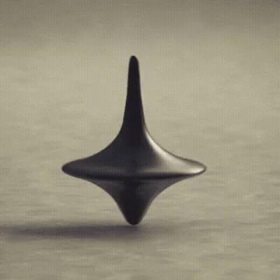 A Black Spinning Top Is Spinning On A Table . GIF