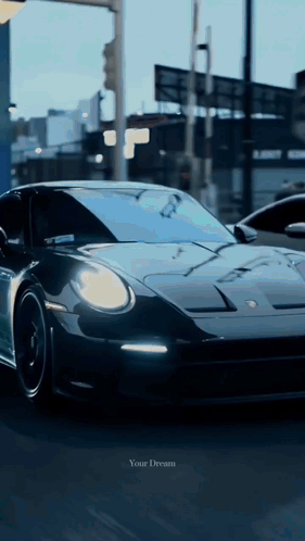 A Black Sports Car Is Driving Down A Street With The Words " Your Dream " On The Bottom GIF