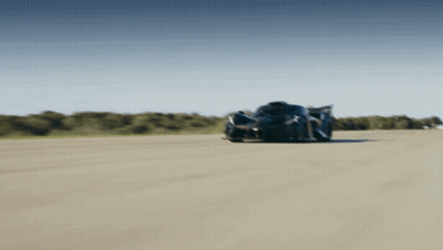 A Black Sports Car Is Driving Down A Track GIF
