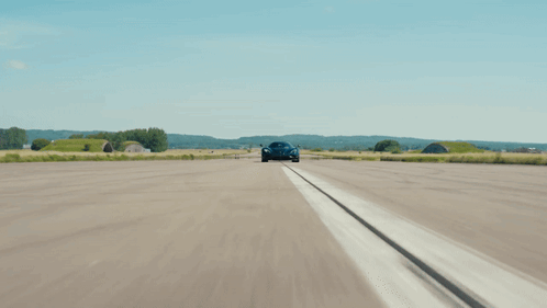 A Black Sports Car Is Driving Down The Road GIF