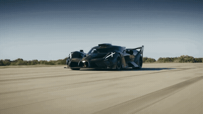 A Black Sports Car With A White X On The Side Of It GIF
