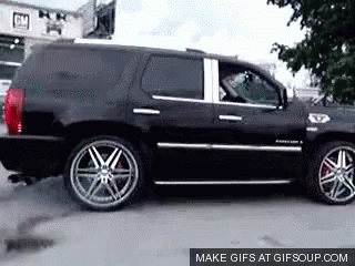 A Black Suv Is Parked In Front Of A Building That Says Gm On It GIF