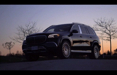 A Black Suv Is Parked On The Side Of A Road With Trees In The Background GIF