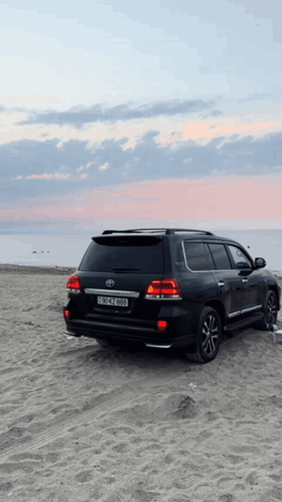 A Black Toyota Suv Is Parked On A Sandy Beach With A License Plate That Says Bscn 888 GIF