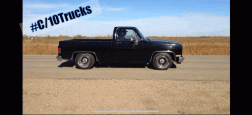 A Black Truck Is Driving Down A Dirt Road With A # C / 10Trucks Sticker Above It GIF
