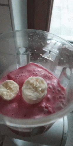A Blender Filled With A Pink Smoothie With Two Banana Slices In It GIF