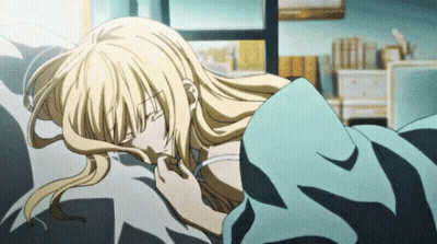A Blonde Anime Girl Is Laying On A Bed With A Blue Blanket GIF